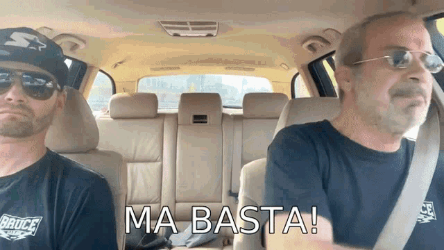 two men in a car with the words ma basta written on the bottom
