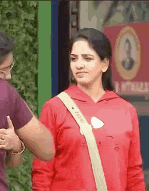 a woman in a red hoodie is standing next to a man in a red shirt .