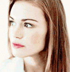 a close up of a woman 's face with long hair and a pink lip .
