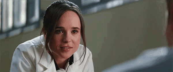 a woman in a white lab coat is looking at the camera .
