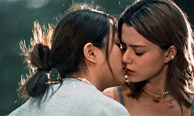 two women are kissing each other and one has earrings in her ear