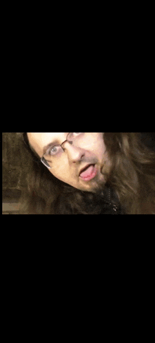 a man with glasses and a beard is looking at the camera .