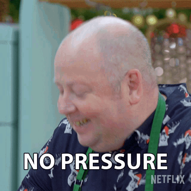 a bald man with a green apron is smiling and says no pressure netflix
