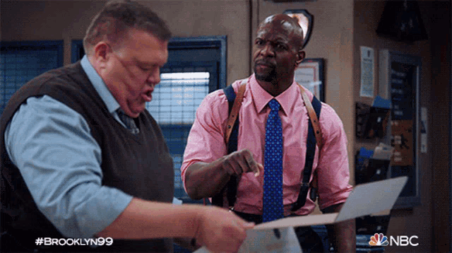 a man in a pink shirt and tie is talking to another man in suspenders