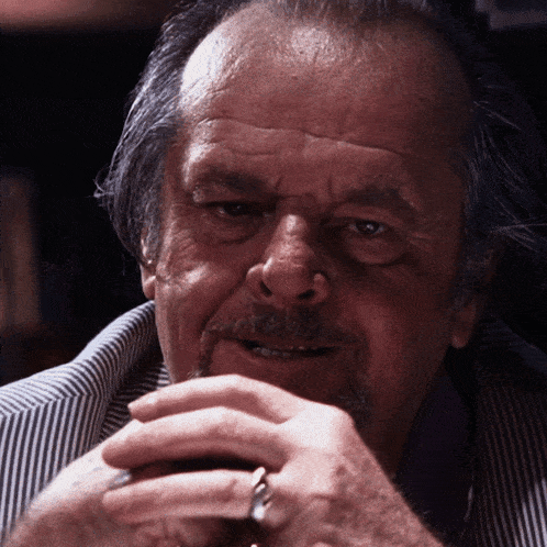 a close up of a man 's face with his hands folded