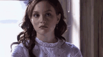 a woman in a white dress is looking at the camera .