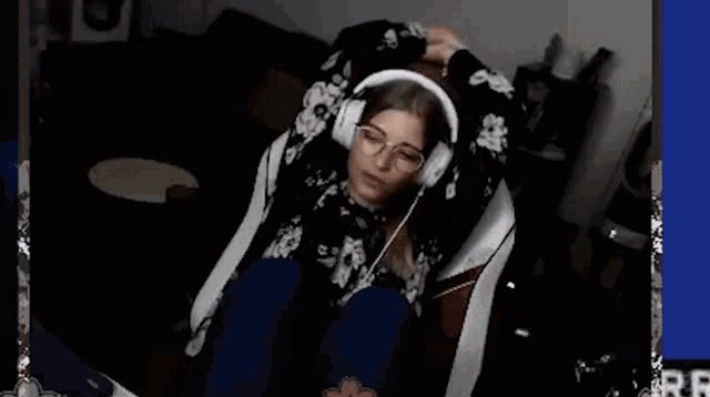 a woman wearing headphones is sitting on a chair with a cat .
