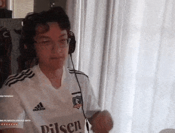 a man wearing headphones and a white adidas shirt is dancing in a room .