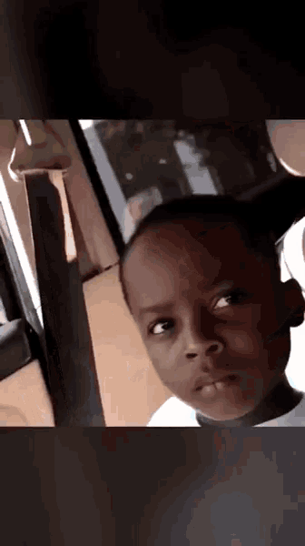 a young boy is looking out of a car window with a serious look on his face