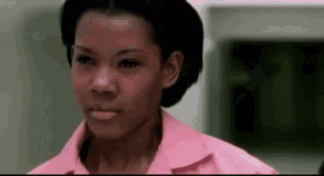 a woman in a pink shirt is looking at the camera and making a funny face .