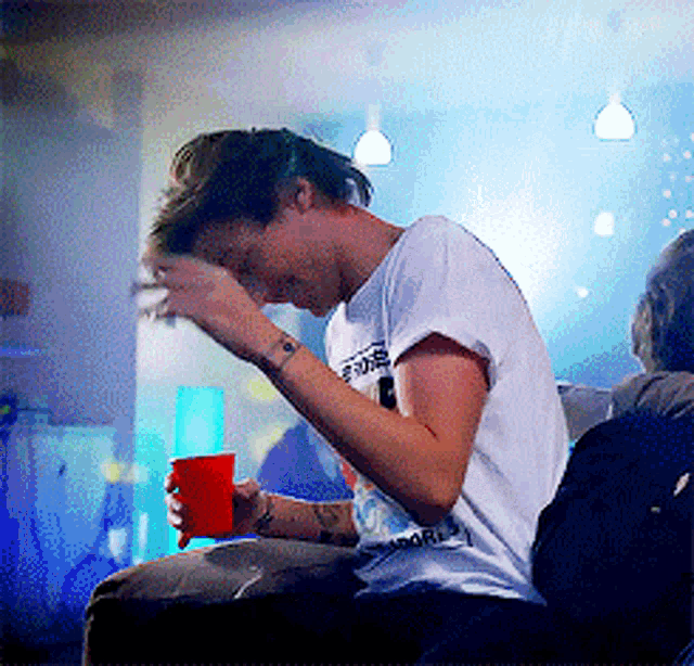 a man wearing a white shirt that says ' i love you ' on it holds a red cup