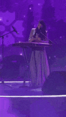 a woman singing into a microphone while playing a keyboard in front of a green background that says ' s '