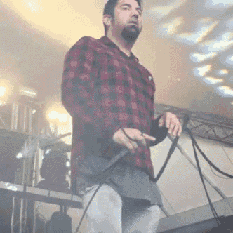 a man in a plaid shirt holds a microphone