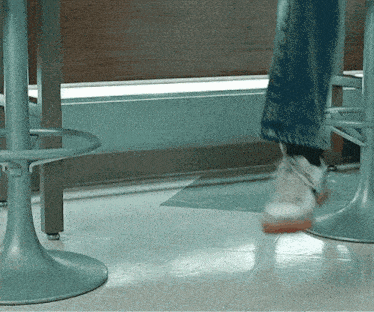 a person 's feet are shown in a blurry photo as they walk past a bar stool