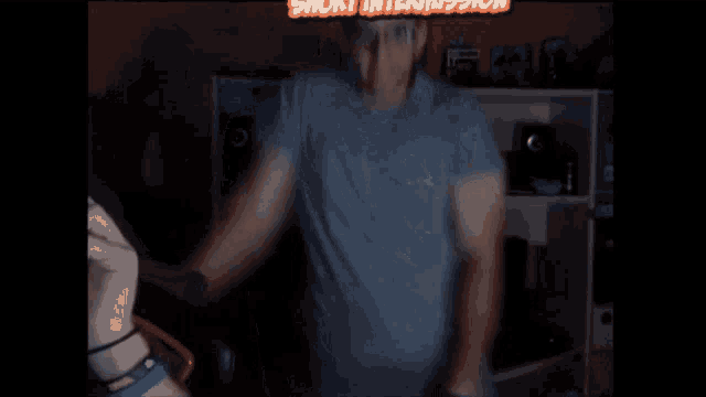 a man in a blue shirt is dancing in front of a sign that says " noise emission "