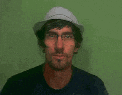 a man wearing glasses and a hat with his tongue hanging out