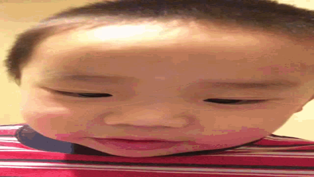 a close up of a baby 's face with a red and white striped shirt