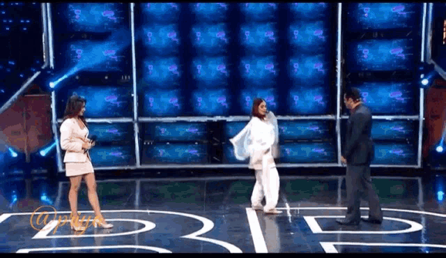 a woman in a white dress is dancing on a stage with a man in a suit standing next to her