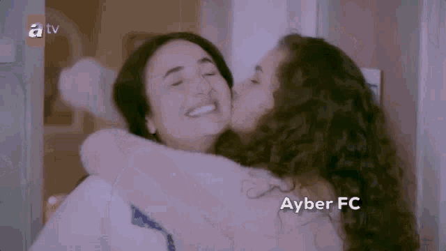 a woman is kissing another woman on the cheek while hugging each other .