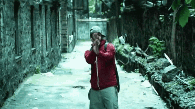 a man in a red jacket is standing in an alleyway