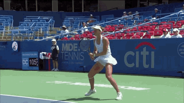 a woman is playing tennis in front of a wall that says citi