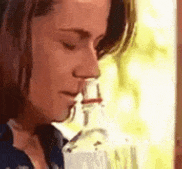 a woman is smelling a bottle of water .