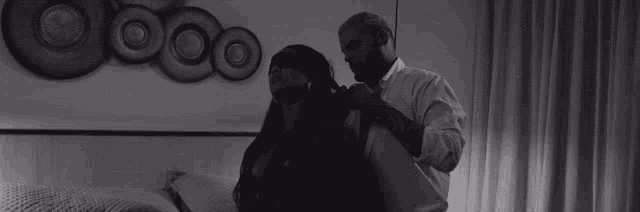 a man is putting a blindfold on a woman 's eyes in a black and white photo