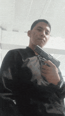 a man in a black jacket holds a gun in his hand