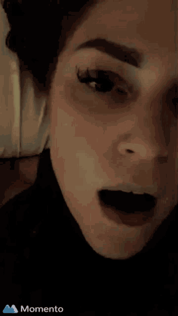 a close up of a woman 's face with a blue momento icon in the corner