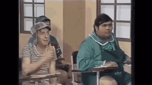 a group of men are sitting at desks in a classroom and applauding .