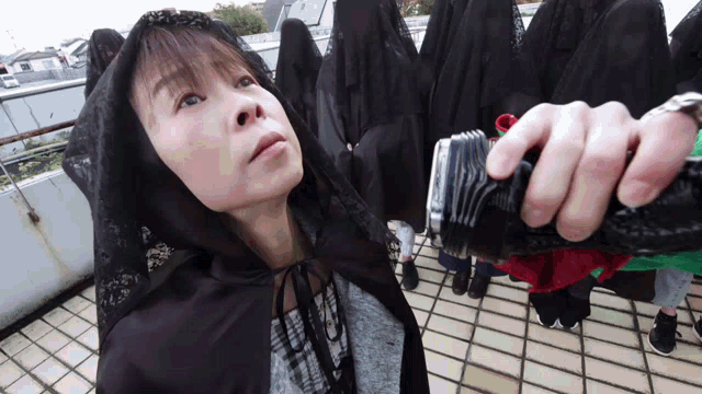 a woman wearing a black cape stands in front of a group of people