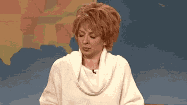a woman in a white sweater is sitting in front of a map of the usa