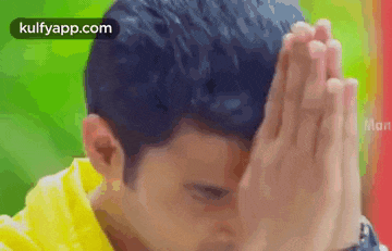 a man is covering his face with his hands in prayer .