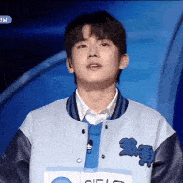 a young man wearing a blue and black jacket with the letter c on the front