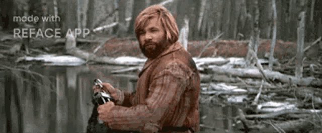 a man with a beard is holding a camera in front of a river .