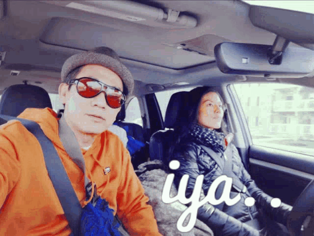 a man and a woman are sitting in a car with the word iya written on the bottom
