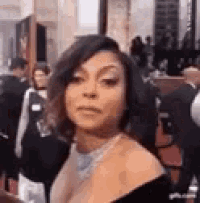 a woman in a black dress is standing on a red carpet in front of a crowd .