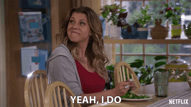 a woman sitting at a table with a plate of food and says yeah i do