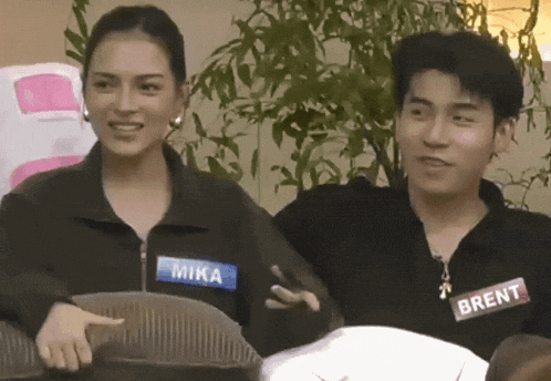 a man and a woman are sitting next to each other and the woman has a name tag that says mika on it