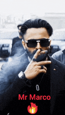 a man in a suit and sunglasses smoking a cigarette with the name mr marco written below him