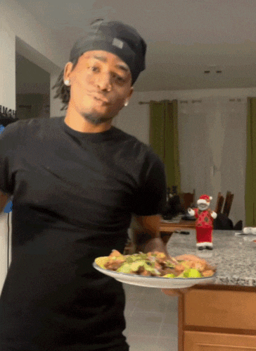 a man in a black shirt is holding a plate of food in front of a santa claus figurine