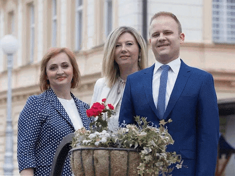 a man in a blue suit and tie is standing next to two women