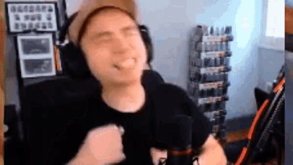 a man wearing headphones and a hat is standing in front of a microphone and making a funny face .