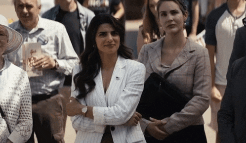a woman in a white striped suit stands next to a woman in a plaid jacket