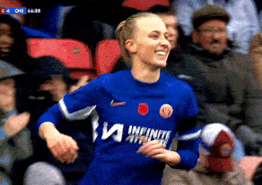 a female soccer player wearing a blue jersey that says infinite