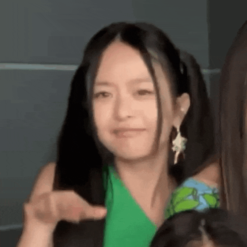 a woman in a green dress is making a funny face while standing next to another woman .