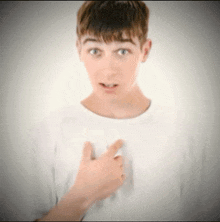 a young boy in a white shirt is pointing at something
