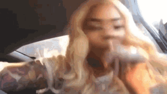 a woman with long blonde hair is sitting in the back seat of a car .