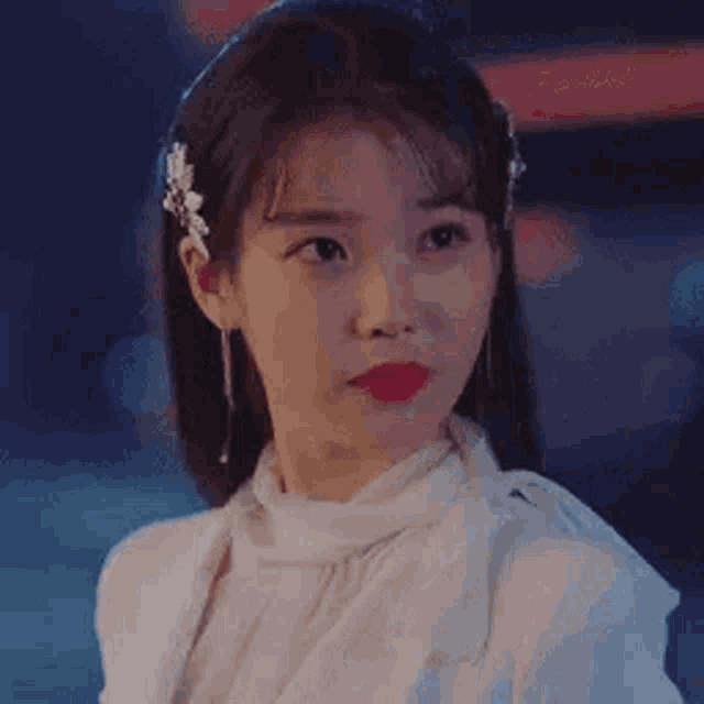 a close up of a woman wearing a white dress and earrings .