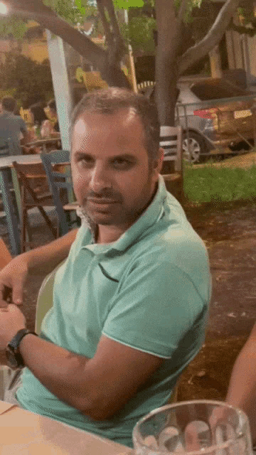 a man in a green polo shirt sits at a table